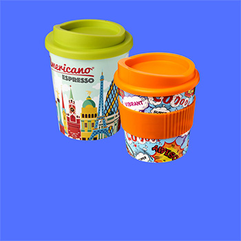 Two Brite-Americano® tumblers on a mid blue background. The tumblers have multicoloured printed designs on the tumblers. One has a lime green lid whilst the other has an orange lid and grip on the tumbler body.